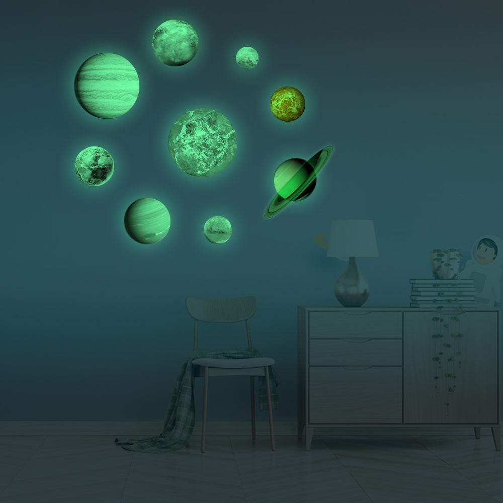 Planet Stickers Solar System glowing in the dark, on a blue wall beside a dresser and chair