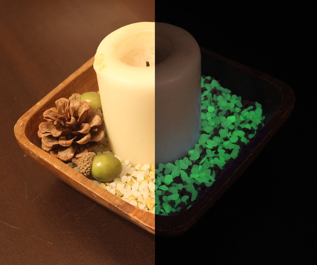 Candle in a wooden dish with a pine cone, acorns and glow granules, daylight on the left, glowing green in the dark on the right
