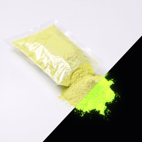 Fine glow pigment Yellow-Green 100 g: cut-open bag and a small heap of fine powder, yellow by day, glowing yellow-green in the dark (lower right)