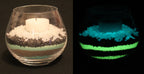 Glow granules in layers in a glass with a candle, in light on the left, glowing in the dark on the right