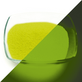 Glow Granules Yellow 1 mm in a glass dish, split view: yellow in daylight on the left, glowing green in the dark on the right