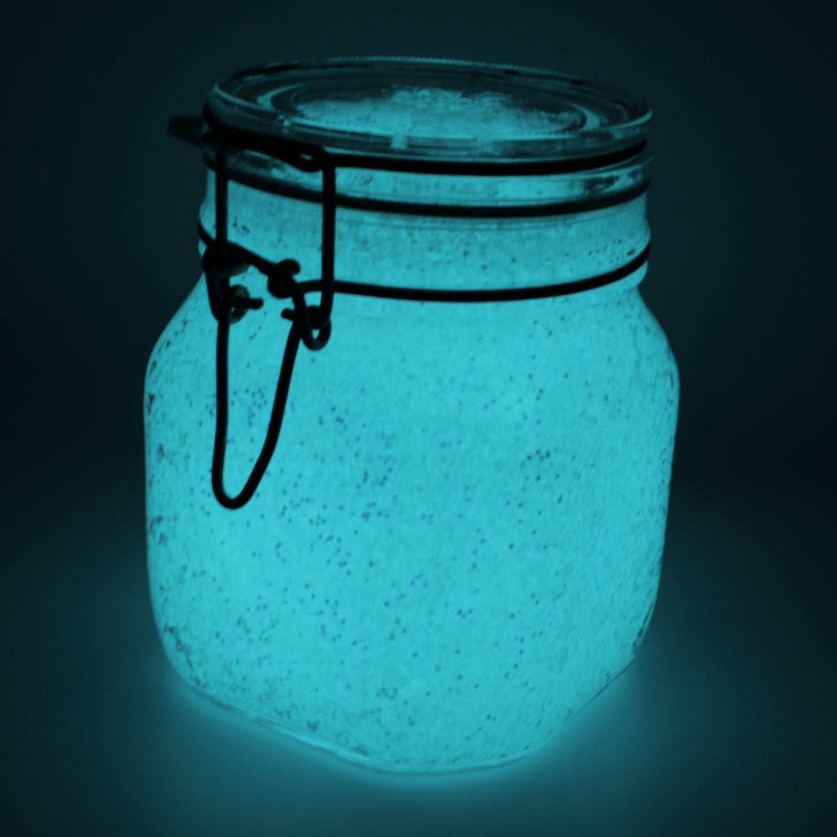 Glow jelly with glitter in a clip-top jar, glowing blue-green in the dark