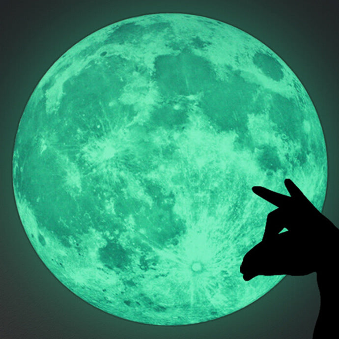 Moon sticker glowing in the dark with the shadow of a hand in front of it