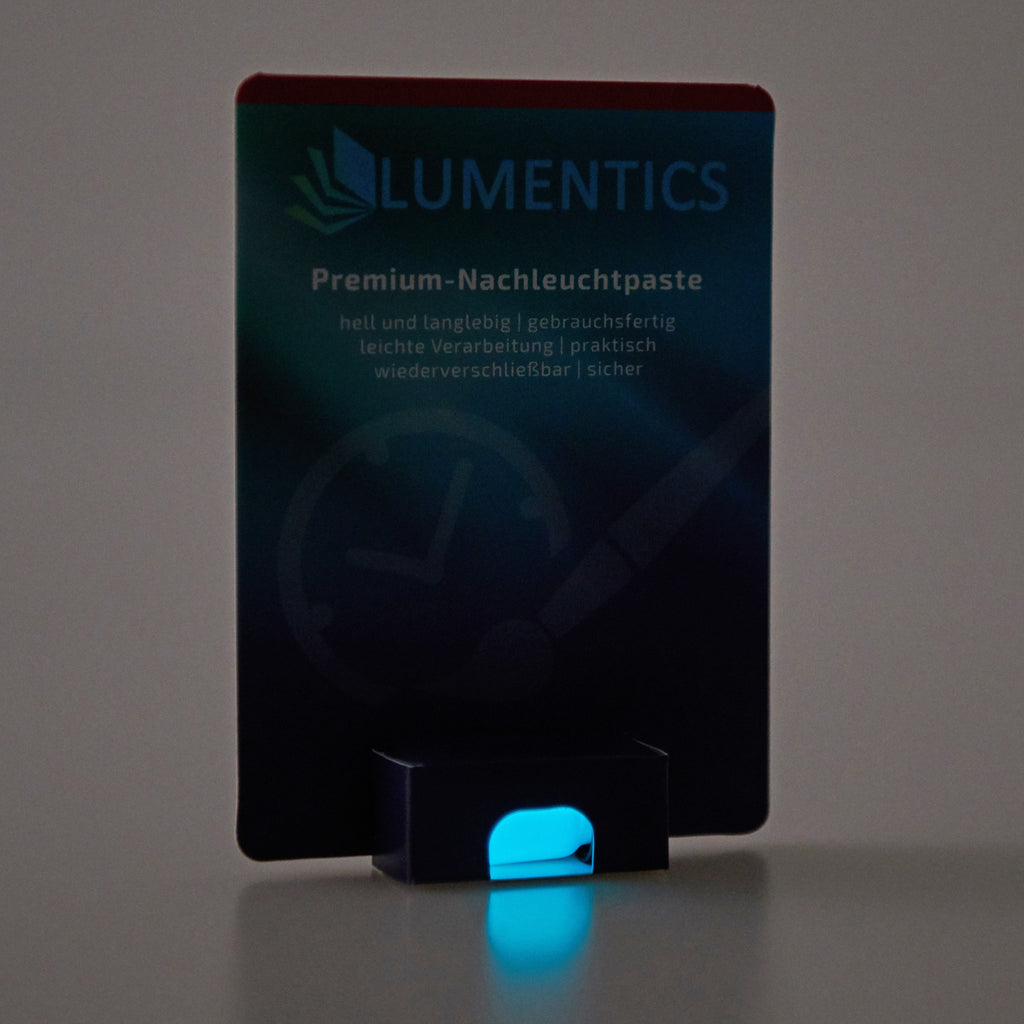 Luminous Paint for Watch Hands Natural Blue-Green 2 g: card in dim light, the paste in the holder glowing blue-green