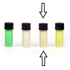 Four small glass vials with colour samples in daylight, green, whitish and yellowish, arrows marking one vial