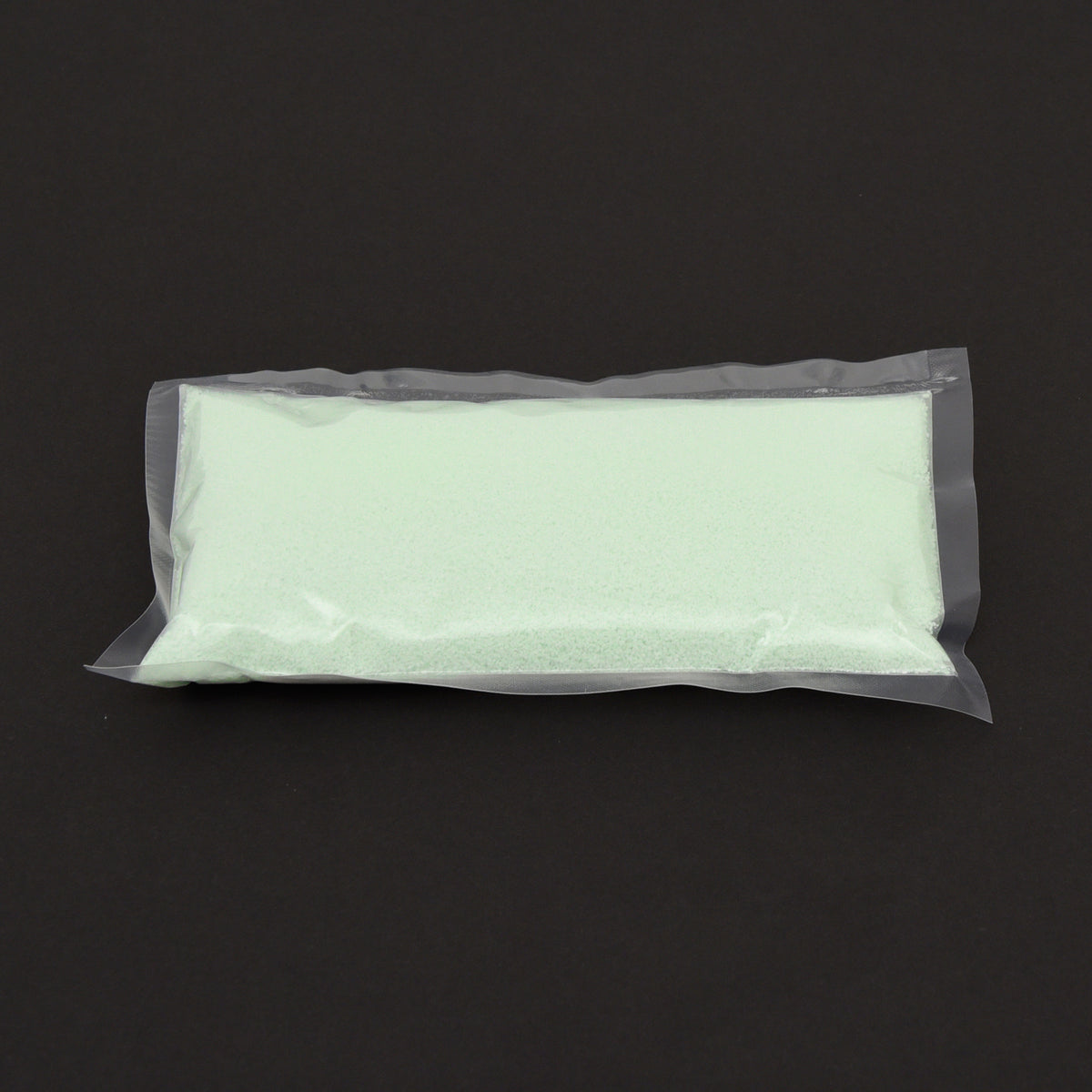 Glow granules 1 mm in a clear bag in daylight, pale green, on a dark background