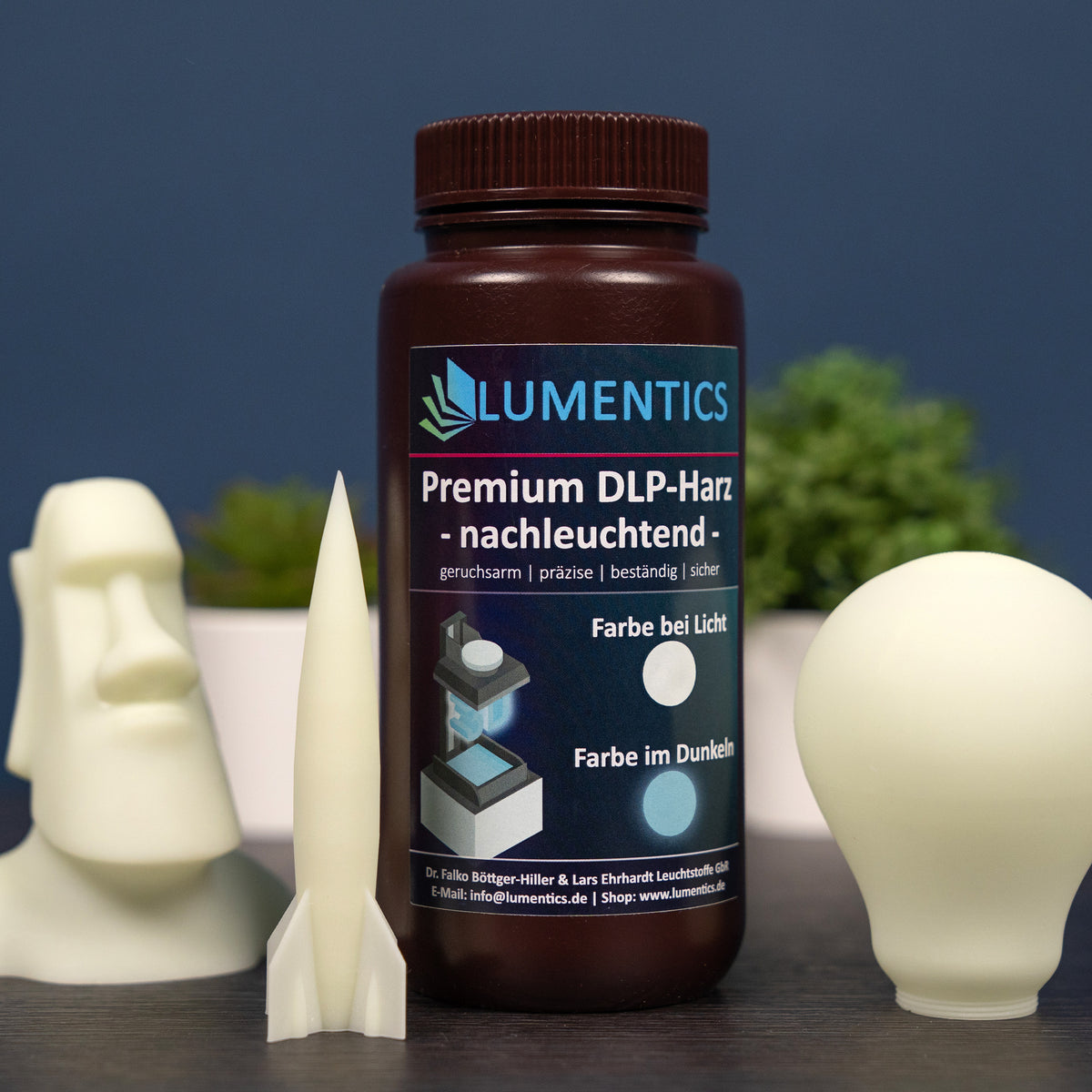 3D Printing Resin Green-Blue 500 g with a printed moai, rocket and light bulb in daylight, cream white