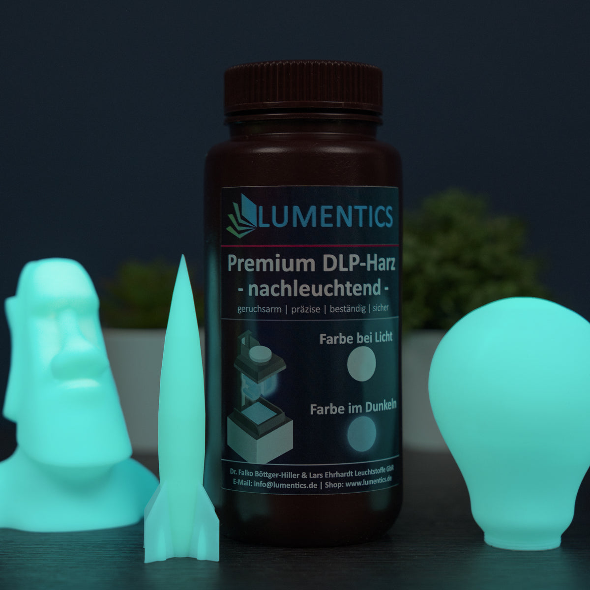 3D Printing Resin Green-Blue 500 g with a printed moai, rocket and light bulb in the dark, glowing green-blue