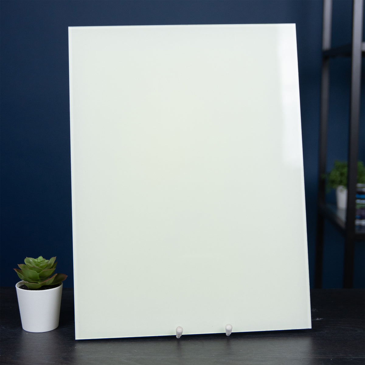 Glow Board A5 on a stand in daylight, whitish, with a plant beside it