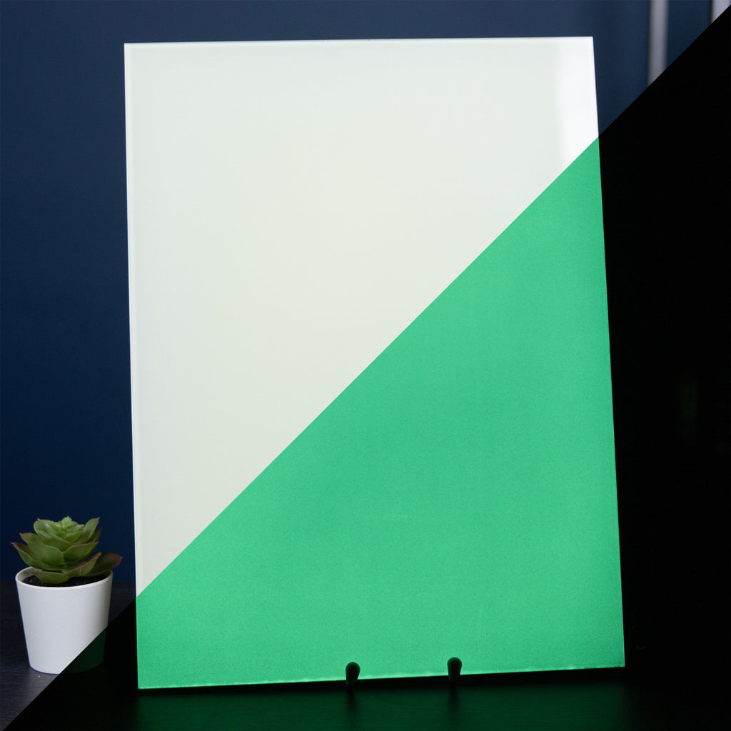 Glow Board A4: board beside a plant, left half whitish in daylight, right half glowing green in the dark