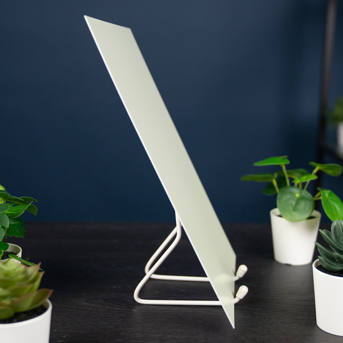Glow Board A5 seen from the side on a wire stand in daylight, pale greenish white