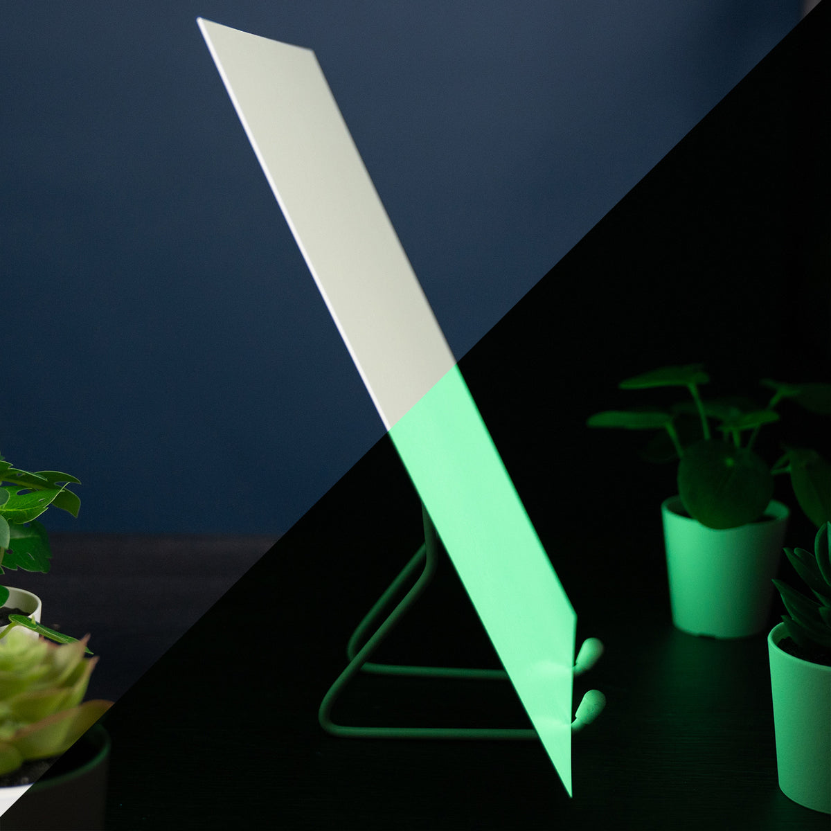 Glow Board A4: side view on a stand, white in light above, glowing green in the dark below