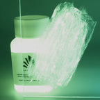 Glitter Glow Paint Yellow-Green 100 g: bottle with a paint stroke on an acrylic sheet in the dark, glowing green