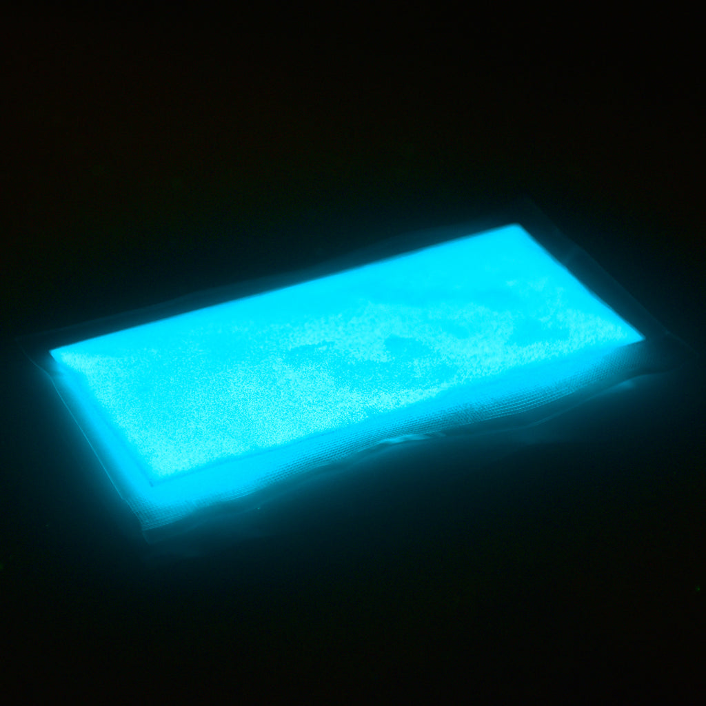 Glitter powder blue-green 50 g in its bag, glowing light blue in the dark