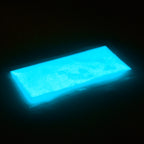 Glitter powder blue-green 50 g in its bag, glowing light blue in the dark