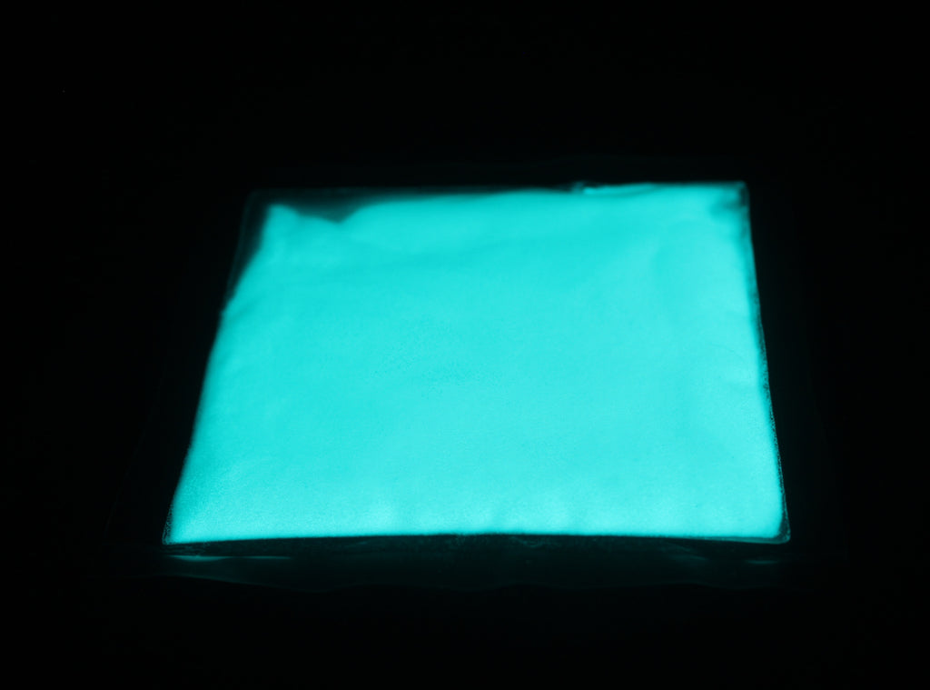 Glow in the Dark Powder Blue-Green 40 g: flat pouch of powder in the dark, glowing pale blue-green