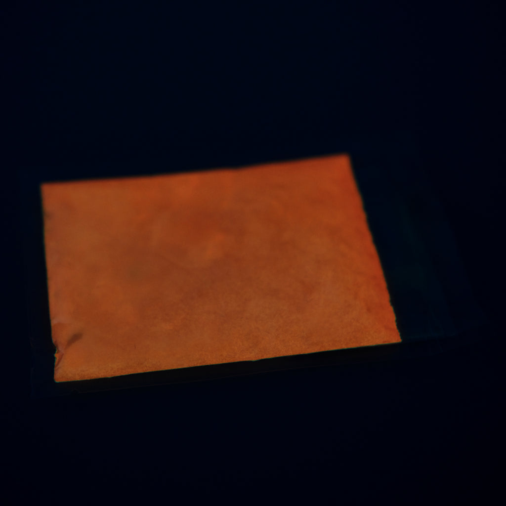 Glow in the Dark Powder Orange 40 g: bag of powder in the dark, glowing orange