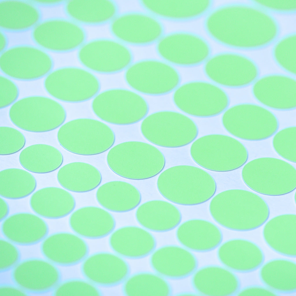 Glow dots in different sizes in close-up, glowing light green on a white sheet