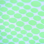 Glow dots in different sizes in close-up, glowing light green on a white sheet