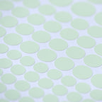 Glow dots in different sizes in close-up in daylight, pale green on a white sheet