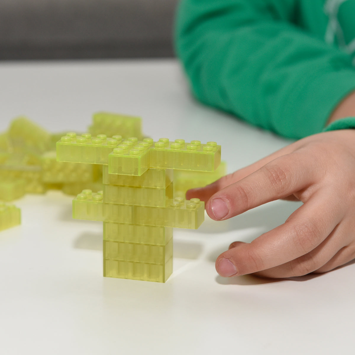 Yellow 2x4 Building Bricks: a childs hand beside a stacked model with a cross beam