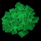 Pile of green 2x4 building bricks in the dark, the bricks glowing green