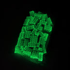 Bag of green 2x4 building bricks in the dark, the bricks glowing green through the film