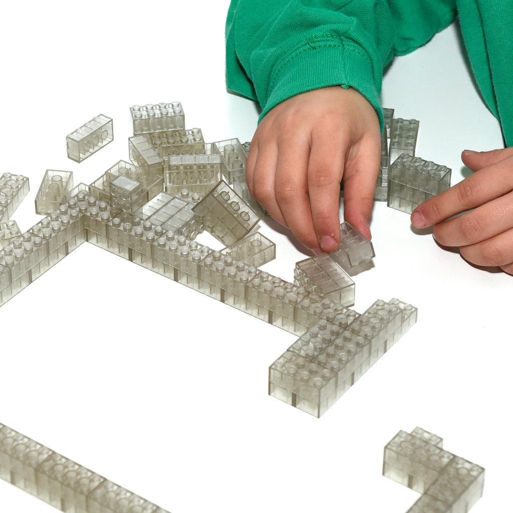 Transparent 2x4 building bricks, hand adding bricks to a long row