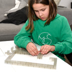 Child building walls from transparent 2x4 building bricks on a table