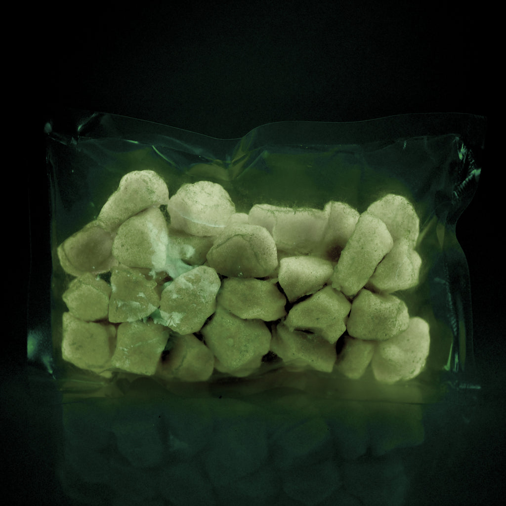 Glow Stones Brown 300 g in a clear bag in the dark, glowing faint green