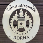 Metal club emblem with powder coating in daylight, pale plaque on a wooden wall