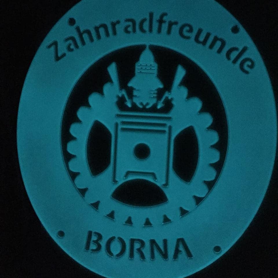 Powder-coated metal club emblem in the dark, glowing blue-green