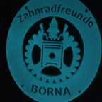 Powder-coated metal club emblem in the dark, glowing blue-green